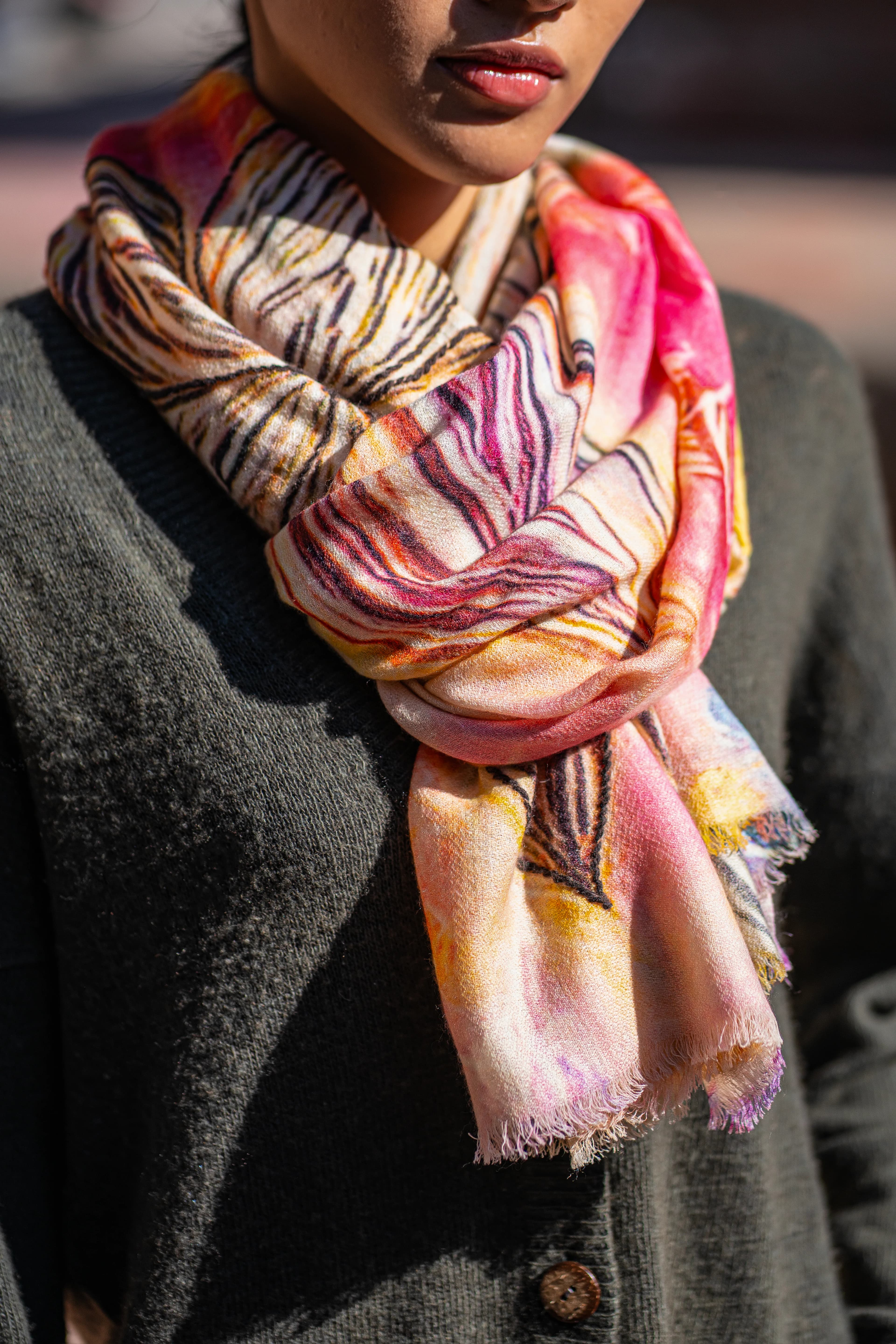 Close-up of a colourful printed cashmere scarf in pink, orange and yellow wrapped around the neck