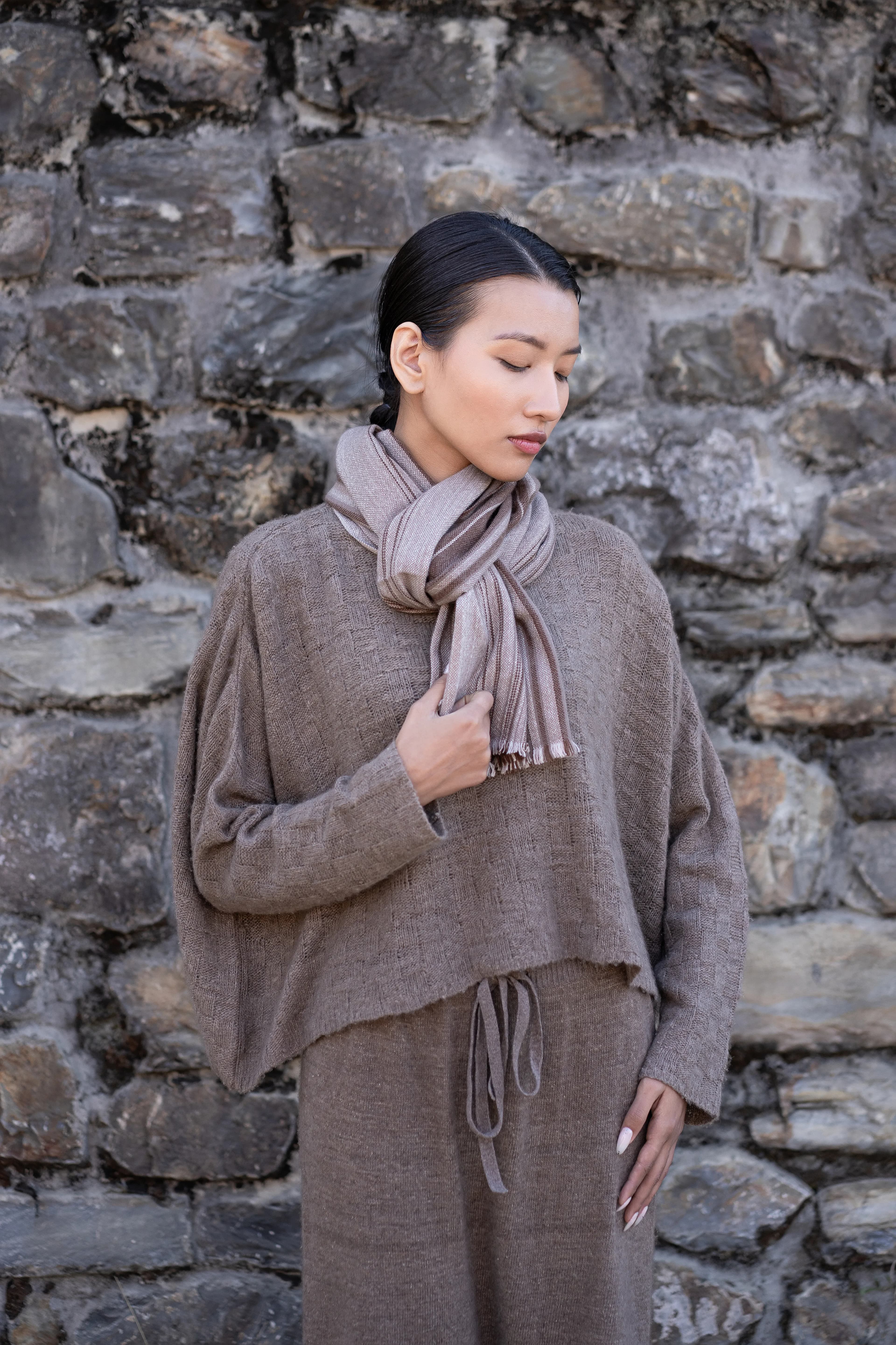 Model wearing a striped cashmere scarf over a textured taupe knit sweater