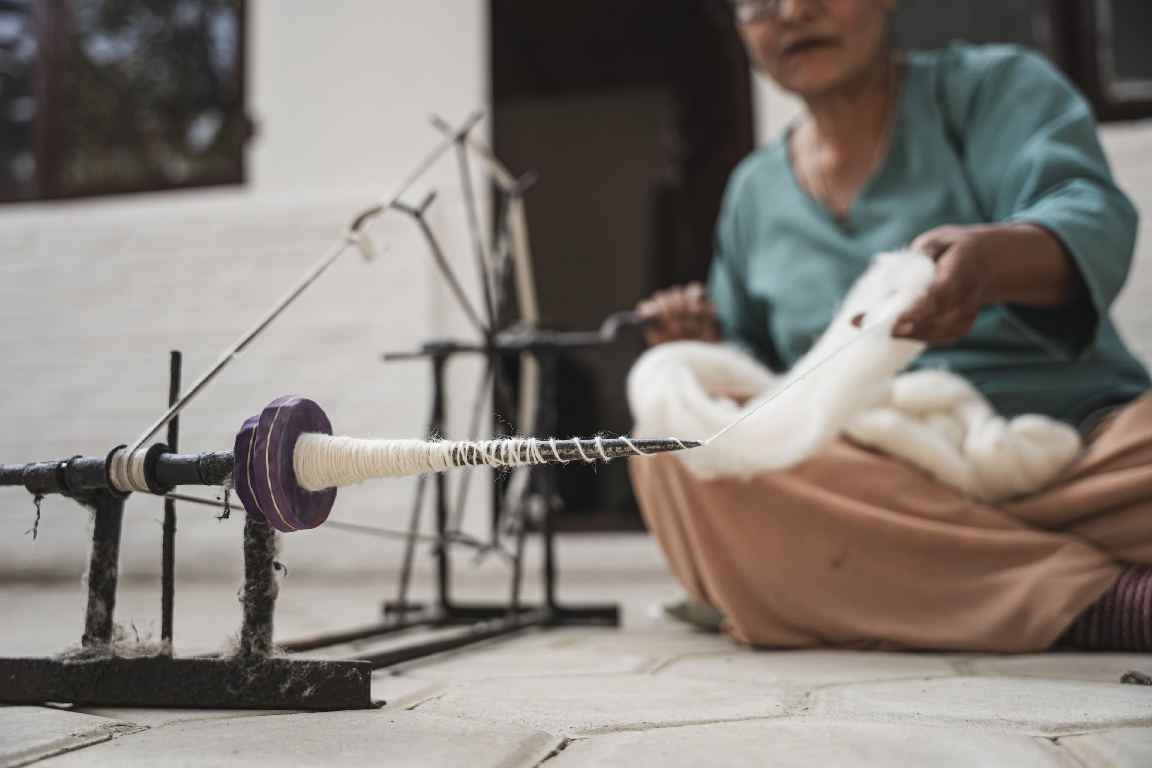 Artisan spinning fine raw cashmere yarn on a traditional spinning wheel